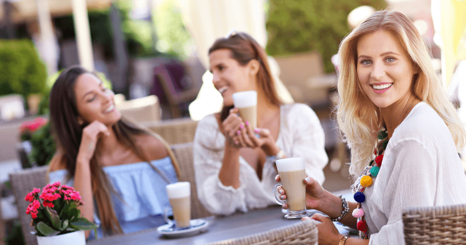 female friends talking over coffee at cafe table outdoors